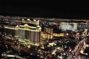 Nächtliches Las Vegas mit Caesars Palace Hotel : Blick vom Nachbau des Pariser Eiffelturms am Las Vegas Boulevard auf das am Abend beleuchtete Las Vegas, aufgenommen am 8. August 2012