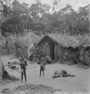 Dorfbild : Familie vor ihrem Haus, im Hintergrund bestelltes Feld
