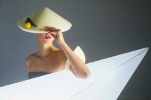 Model in Schaumstoffmode : Model mit gelbem Schaumstoffhut hinter einem Neonleuchtkörper