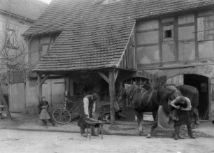 Dorfschmiede : Hufschmiede beim Beschlagen der Hufe vor der Schmiede