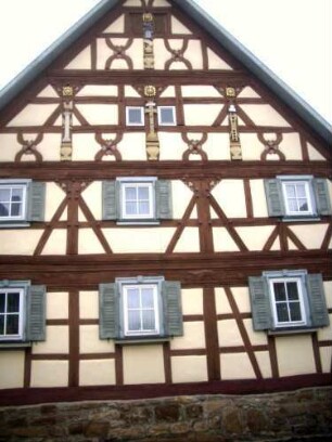 Fachwerkhaus gegenüber der Kirchenburg über Giebelseite mit Holzschnitzerei in Farbigkeit sowie Fachwerk mit Holznägeln