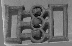 Altitalische Gürtelschlieβe. Die beiden äußeren Haken gehen in primitive Pantherköpfe aus, der mittlere in weiblichen Kopf (Gesicht zerrieben) mit symmetrischen Spirallocken