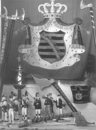 Bermännische Porzellanfiguren von Braunschmidt, Sächsische Porzellanfabrik Freital-Potschappel, vor Knappschaftsfahne, Bergmannsbarte und Steigerhäkchen. Freital-Burgk, Haus der Heimat