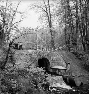 Brücke des Mühlenredder über dem Abfluss des Schlossgrabens: Renovierung: Seitenansicht von Norden: rechts unterhalb der Brücke Grundablassrohr: oben Arbeiter beim Aufbringen eines Schwarzteerbelags