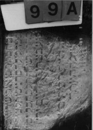 Grabstein 99 (Index: 99792178) Material: Sandstein Zustand: verwittert mit Textverlust, Stele liegend Maße HxBxT: 69x56x10 cm Beschreibung: Stele, Segmentbogenabschluß, rechteckiges Schriftfeld eingetieft: Grabstein 99A
