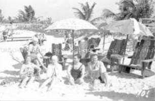 Touristen am Strand unter Sonnenschirmen sitzend