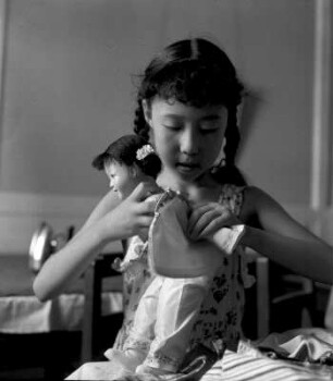 Mädchen beim Anziehen seiner Puppe : Chengdu (China). Mädchen beim Anziehen seiner Puppe