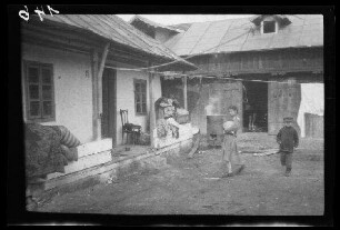 Odobești (=Rumänien): einheimische Familie im Hof ihres einfachen landwirtschaftlichen Anwesens, im Hintergrund ein Stall (Distanzaufnahme)
