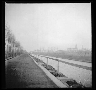 Comines-Warneton (Belgien): Weg (Knüppelpfad (?)) mit Holzgeländer am Kanal, im Hintergrund eine Kirche [Saint-Chrysole] ("Belgisch-Comines mit Kanal")