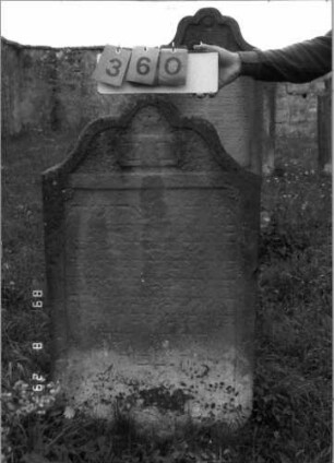 Grabstein 360 (Index: 100107814) Material: gelber Sandstein Zustand: stark verwittert, weitgehender Textverlust Maße HxBxT: 114x66x11 cm Beschreibung: Stele in Sonderform (geschwungen eingezogener Kleeblattbogen), Schriftfeld rechteckig eingetieft Symbolik: Rosette Besonderheit: keine Zuordnung nach Sterberegister möglich: Grabstein 360