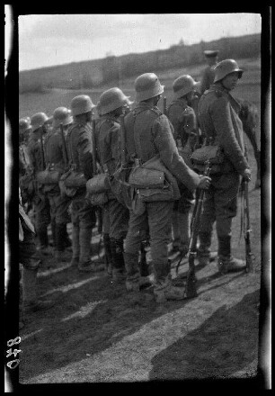 Übungsgelände I bei Mouzon (Dep. Ardennes, Frankreich): Soldaten mit Stahlhelm und voller Ausrüstung in einer Zweierreihe (seitliche Rückansicht)