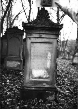 Grabstein 92 (Index: 99751855) Material: Sandstein Zustand: leicht verwittert Maße HxBxT: 157x49x24 cm Beschreibung: Stele, profil. Sock/Abdeckplatte m. Volutenaufsatz m. Palmette/rechteck. Schriftfeld Symbolik: Voluten, Palmette: Grabstein 92