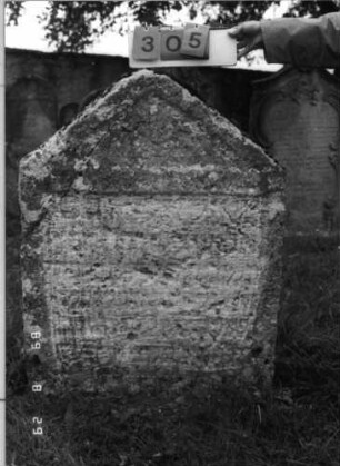 Grabstein 305 (Index: 100107716) Material: Kalkstein Zustand: verwittert, völliger Textverlust Maße HxBxT: 114x88x20 cm Beschreibung: Stele mit Giebelabschluß, Schriftfeld rechteckig eingetieft: Grabstein 305