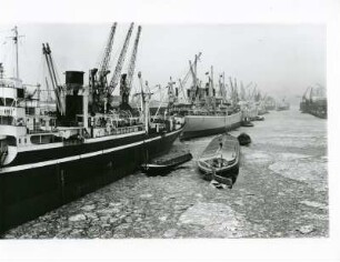 Hamburg. Der Hafen im Winter. Schlepper und Lastkähne bahnen sich ihren Weg durch das teileweise vereiste Hafenbecken