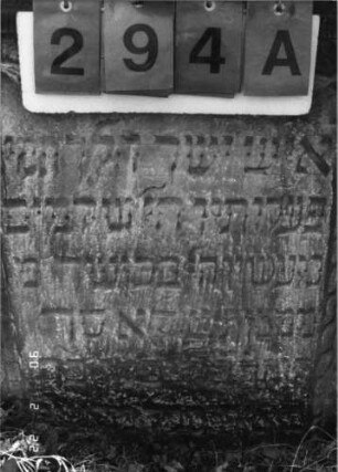 Grabstein 294 (Index: 100115889) Material: Sandstein Zustand: stark verwittert, zum Teil im Boden versunken Maße HxBxT: 92x66x11 cm Beschreibung: Stele mit konkav eingezogenem, überragendem Segmentbogenabschluß, eingetieftes Schriftfeld Symbolik: Levitenkanne, Ranken: Grabstein 294A (Detailaufnahme 1)