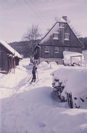 Erzgebirge. Verschneite Dorflandschaft mit Skifahrer