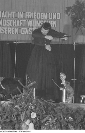 Eine Puppenspielerin mit einer Marionette in Gestalt eines Clowns auf einer Betriebsweihnachtsfeier