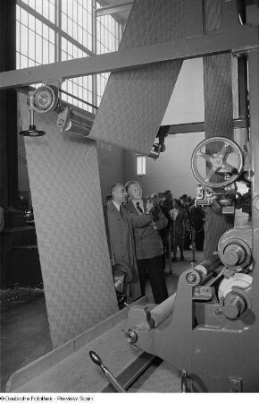 Besucher der Leipziger Herbstmesse 1954 betrachten eine Textilmaschine