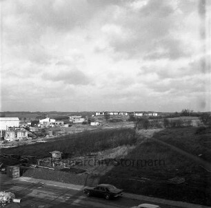 von den Straßen Im Hölk und Poggenbreeden umschlossenes Bauland, rechts dahinter Baustelle, mittig Wohngebäude, im Hintergrund Wohngebäude des Fuchsberg: Blick nach Nordwesten