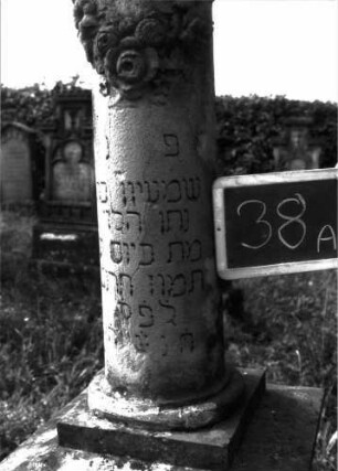 Grabstein 38 (Index: 100100871) Material: Sandstein Zustand: Säule leicht beschädigt Maße HxBxT: 185x54x54 cm Beschreibung: Säulenstumpf, getreppter Sockel, unterster Sockelteil rusticaartig Symbolik: Blumenkranz um Säulenstumpf: Grabstein 38A