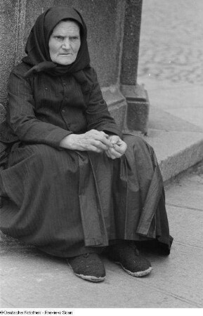 Porträt einer alten Frau an einem Brunnen
