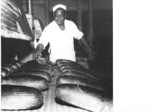 Frankfurt (Main). Großbäckerei. Bäckerlehrling aus Nigeria beim Bestreichen von Broten
