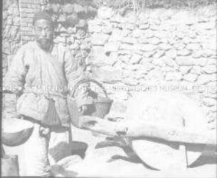 Glasdia von einem alten chinesischen Mann vor einer großen Handmühle