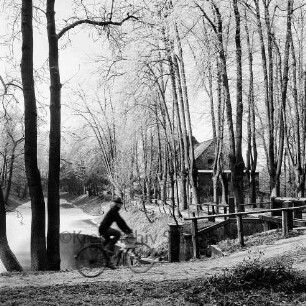 Schlossmühle: Mühlenredder, Bäume, vorne rechts Brücke des Mühlenredder über dem Abfluss des Schlossgrabens: links äußerer Schlossgraben mit Eisdecke: vorne auf Parkweg Fahrradfahrer [bewegungsunscharf]: Rauhreif: im Winter