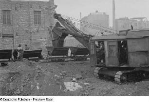 Blick auf eine Baustelle mit einem Bagger, der Loren befüllt
