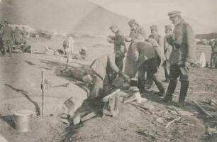 Biwak auf der Mazedonischen Hochebene, Soldaten (Ca. fünfzehn Personen) vorwiegend beim Essen, feldmässige Ausrüstungsgegenstände liegen auf Erdboden verteilt