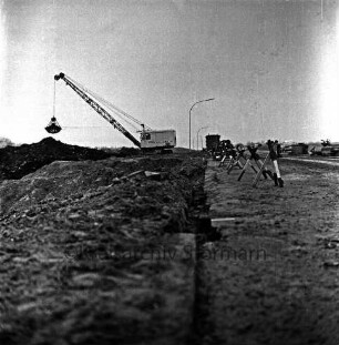Industriestraße: Absackung eines Teilstücks: vorn Absperrung und Erdhaufen: dahinter Bagger und Baubude: hinten rechts Pkw