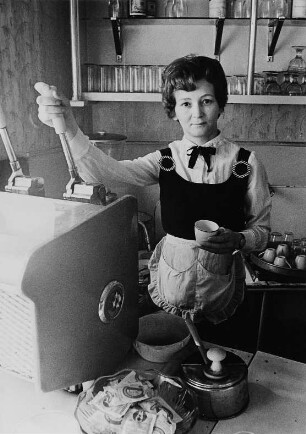 Serviererin an einer Espressomaschine