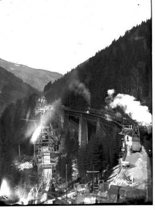 Blick von oberhalb des Westportals des Ravennatunnels auf die Arbeiten an den Pfeilern des neuen Viaduktes und auf den alten Viadukt mit darauf befindlichem Eisenbahnzug