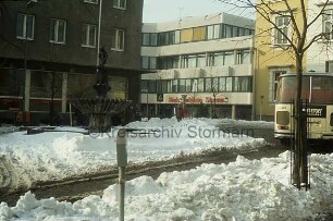 Marktplatz: vorn Schneehaufen: links Gänseliesel-Brunnen vor Altbau der Kreissparkasse Stormarn: rechts Bus vor Rathaus: hinten Mitte Neubau der Kreissparkasse an Hagenstraße: Winter