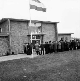 Klein Barnitz: Wasserwerk Klein Barnitz des Wasserbeschaffungsverbands Reinfeld-Land: Einweihung: Außenansicht mit Schleswig-Holstein-Flagge: davor Vertreter des Landesamtes für Wasserwirtschaft, des Wasserwirtschaftsamtes Lübeck, des Wasserbeschaffungsverbandes Reinfeld-Land, Kreispräsident Friedrich Hardt, Bürgervorsteher Jungk, Reinfeld, Bürgermeister Richard Hingst, Reinfeld, Amtmann des Amtes Reinfeld-Land, Tidow sowie Ehrengäste