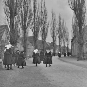 Frauen in Spreewälder Kirchgangstracht auf dem Weg zur Kirche in Dissen. : Žony w Błótowskej kemšacej drasće ducy do cyrkwje w Dešnje.