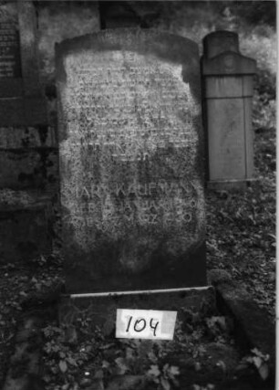 Grabstein 104 (Index: 100079694) Material: Granit Zustand: gut Maße HxBxT: 125x57x15 cm Beschreibung: Stele, Sockel, Segmentbogenabschluß: Grabstein 104