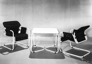 Berlin. VEB Möbelkombinat Berlin (MKB). Hausmesse, 1986. Zwei Armlehnstühle mit Klubtisch. Metall, weiß beschichtet, Holz, Polsterung mit Mischgewebebezug, blauschwarz (1986; VEB Möbelkombinat Berlin (MKB))