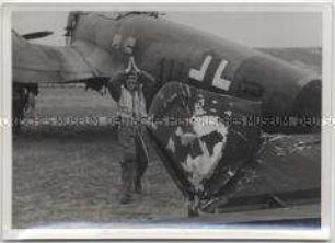 Deutscher Soldat vor seinem beschossenen Kampfflugzeug der deutschen Luftwaffe