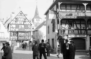Turckheim: Gasse am Tor und Kirchturm, rechts Fachwerkhaus mit Balkons