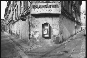 Hausfassade an einer Straßenecke mit Inschrift "Haarfärber" und Telefon