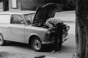 Mann an der geöffneten Motorhaube seines PKW "Trabant"