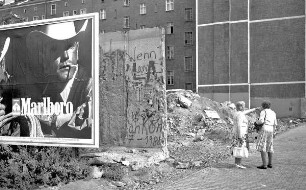 Reste der Berliner Mauer mit "Marlboro Mann" und 2 Passantinnen