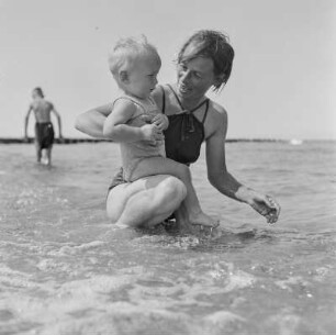 Frau in Bademode und Kleinkind im Meer