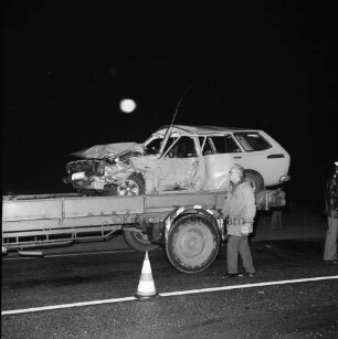 B 404: bei Wolkenwehe: Verkehrsunfall: Auffahrunfall und Zusammenstoß von drei Pkws: Unfallfahrzeug mit eingedrückter Karosserie auf Ladefläche von Abschleppwagen, Abschlepper mit Arbeitshandschuhen: rechts Polizist [angeschnitten]: auf Fahrbahnmarkierung Leitkegel: im Dunkeln