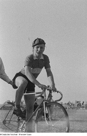 Radrennfahrer, von einer weiteren Person gestützt