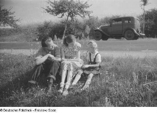 Renate und Roger Rössing mit einem Mädchen am Straßenrand sitzend