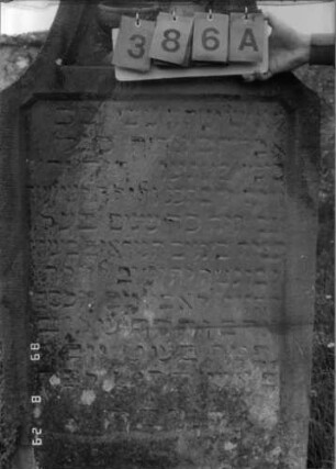 Grabstein 386 (Index: 100107864) Material: gelber Sandstein Zustand: stark verwittert und versalzen, teilweiser Textverlust, Buchstaben schwarz ausgemalt Maße HxBxT: 162x78x16 cm Beschreibung: Stele mit geschwungen eingezogenem übehöhtem Bogenabschluß, Schriftfeld rechteckig eingetieft Symbolik: Levitenkanne und -schale: Grabstein 386A