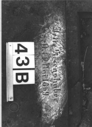 Grabstein 43 (Index: 100105904) Material: Sandstein Zustand: Stein liegend, quer gebrochen mit Textverlust Maße HxBxT: 133x60x17 cm Beschreibung: rechteckige Stele, Sockel, Schriftfeld eingetieft mit Spitzbogenabschluß Symbolik: Maßwerk: Grabstein 43B (1)