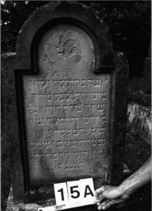 Grabstein 15 (Index: 99802035) Material: Sandstein Zustand: verwittert Maße HxBxT: 148x51x24 cm Beschreibung: Stele, getreppter Sockel, eingezogener Rundbogenabschluß: Grabstein 15A